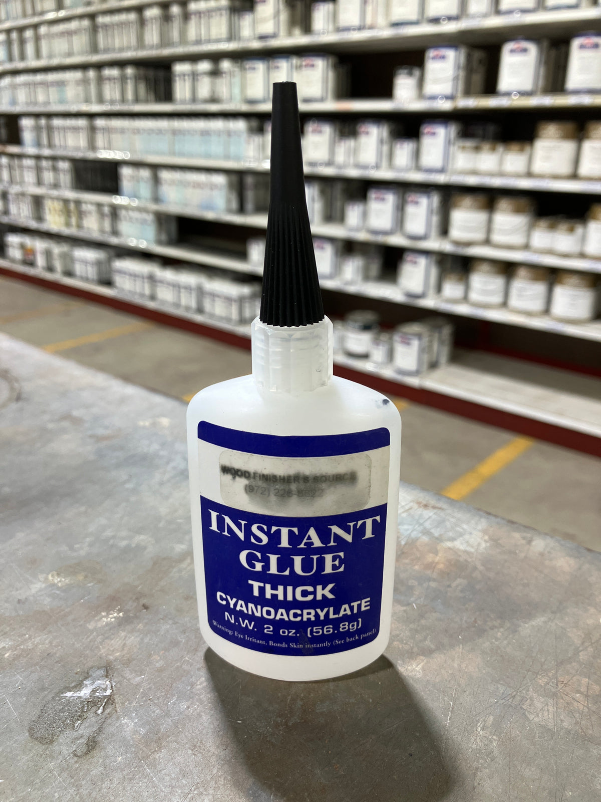 Bottle of instant glue thick on a concrete surface with blurred warehouse background